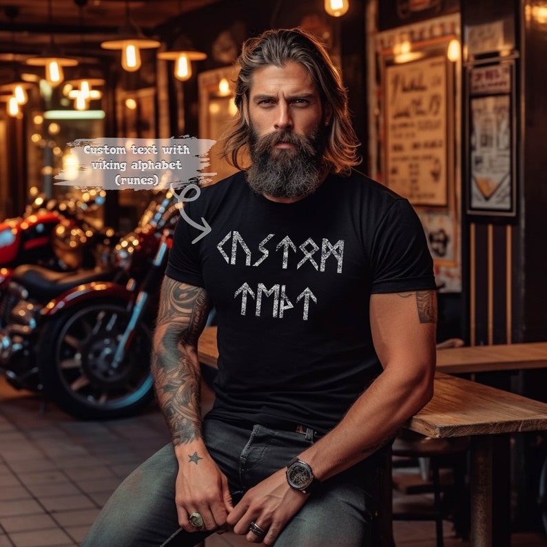 Puede incluir: Una camiseta negra con un dise&ntilde;o blanco de la palabra "CUSTOM" escrita en el alfabeto vikingo (runas).