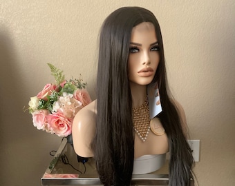 May include: A mannequin head with long, straight, dark brown hair. The mannequin wears a gold and pearl necklace. The head is on a silver table with a glass top. A bouquet of pink and white flowers is to the left.