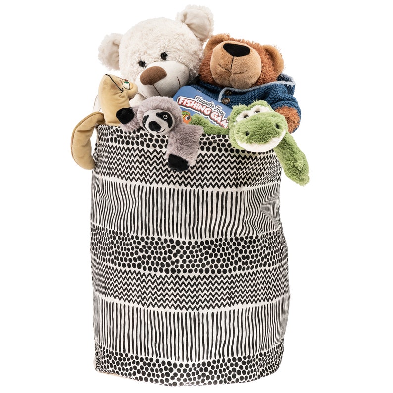 May include: A black and white patterned fabric storage bin filled with stuffed animals, including a white bear, a brown bear, a green frog, and a gray sloth. The bin has a geometric pattern of stripes, dots, and zigzags.