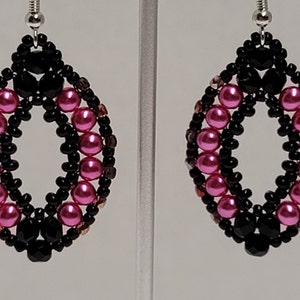 May include: A pair of dangle earrings with a black and pink beaded design. The earrings are made with small, round beads in a teardrop shape.
