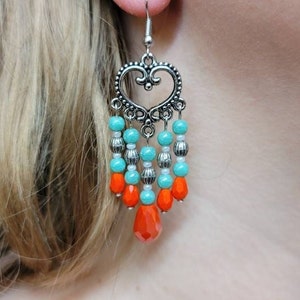 May include: Silver heart-shaped dangle earrings with turquoise and orange beads.