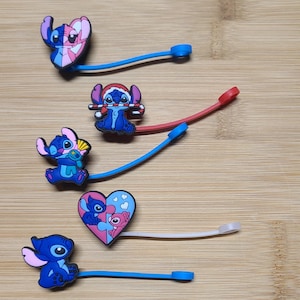 May include: Five colorful silicone Stitch character charms with attached elastic bands. The charms feature Stitch in various poses, including holding a candy cane, a heart, and a flower.