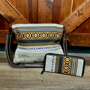 May include: A crossbody bag and a matching rectangular wallet featuring a woven textile pattern in yellow, blue, green, and white. The bag has a dark brown leather strap and a textured gray fur-like base, while the wallet has a black zipper.