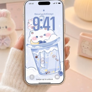 May include: A smartphone with a clear case displaying a digital wallpaper of a light blue bubble tea drink with a cartoon bear face, topped with whipped cream, berries, and a crescent moon, featuring the text BlessingsArtDesign and 9:41.