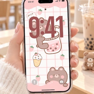 May include: A smartphone with a clear protective case displaying a digital wallpaper featuring a brown bear drinking bubble tea, a strawberry ice cream cone, and small strawberries on a light pink grid background with the time 9:41 displayed.