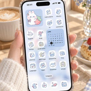 May include: A smartphone displaying a custom digital interface with light blue and white pastel icons. The screen features a calendar widget for June, a large rabbit graphic, and various app labels including calculator, music, tv, and contacts.