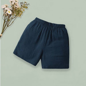 K&ouml;nnte beinhalten: Dunkelblaue Shorts mit elastischem Bund. Die Shorts sind aus einem strukturierten Stoff gefertigt und eignen sich f&uuml;r Freizeitkleidung. Ein Zweig mit wei&szlig;en Blumen befindet sich in der oberen linken Ecke des Bildes.