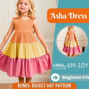 Op de afbeelding: Een mouwloze meisjesjurk met een gelaagd ontwerp in oranje ruitjes, gele strepen en roze stippen. De jurk heeft strikdetails op de schouders. De afbeelding bevat de tekst "Asha Dress", "Back View", "6M-10Y", "Beginner Friendly" en "Bonus: Bucket Hat Pattern".