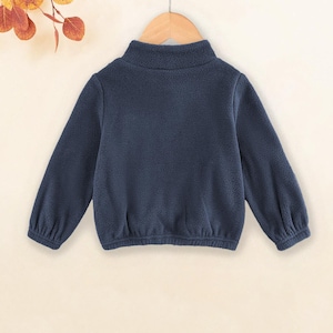 May include: A dark blue fleece pullover with a mock neck and long sleeves. The pullover has a gathered elastic waistband.