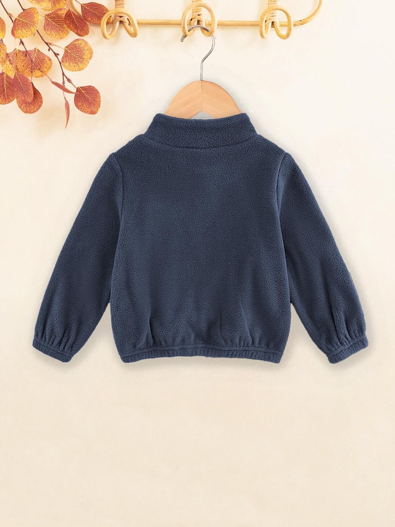 May include: A dark blue fleece pullover with a mock neck and long sleeves. The pullover has a gathered elastic waistband.