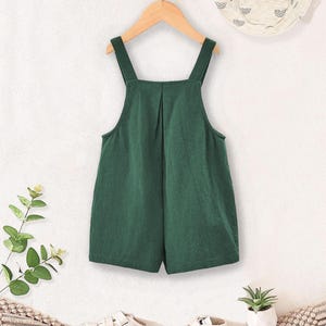 May include: A green overall romper with adjustable straps. The romper is made of a soft, comfortable fabric and has a relaxed fit.