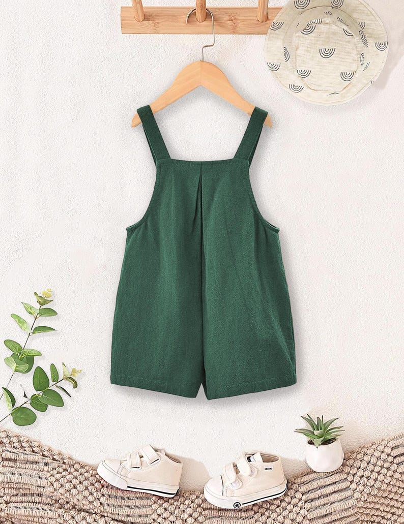 May include: A green overall romper with adjustable straps. The romper is made of a soft, comfortable fabric and has a relaxed fit.
