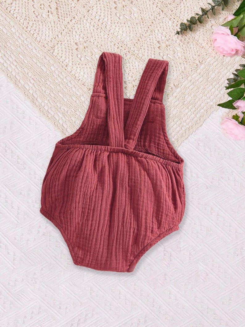 Puede incluir: Un mono de beb&eacute; de color burdeos con tirantes ajustables. El mono est&aacute; hecho de una tela suave y texturizada.