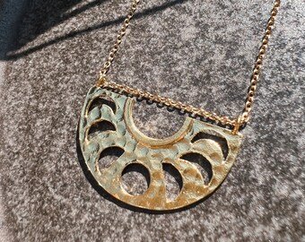 May include: A gold necklace with a crescent moon pendant featuring a hammered texture and cut-out moon phases.