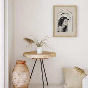 K&ouml;nnte beinhalten: Eine gerahmte Schwarzwei&szlig;illustration einer Frau mit H&ouml;rnern und einem Halbmond &uuml;ber ihrem Kopf. Der Text "Taurus" befindet sich unter dem Bild.