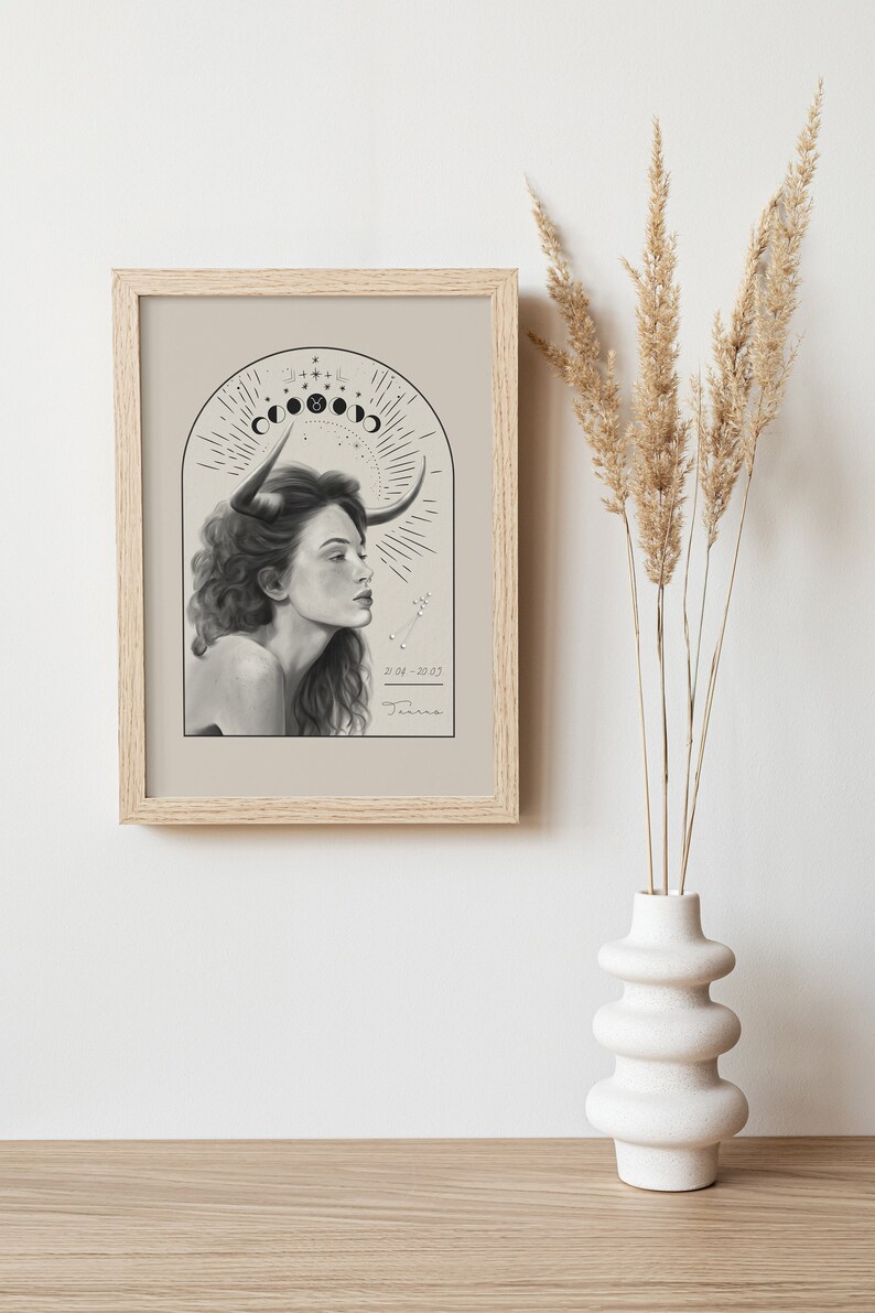 K&ouml;nnte beinhalten: Ein gerahmter Druck einer Schwarzwei&szlig;illustration einer Frau mit Stierh&ouml;rnern, umgeben von einem Halbmond und Sternen. Der Text "Taurus 20/04-20/05" befindet sich am unteren Rand des Drucks.
