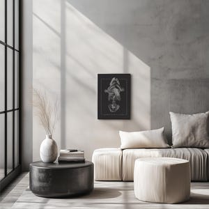 May include: A black and white illustration of a person's skeleton with their arms crossed over their chest. The illustration is framed and hanging on a wall above a white couch.