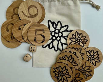 May include: Wooden game pieces with numbers and flower designs. Includes a drawstring bag with a black flower graphic and two dice. The word "Hickory" is written in blue at the top of the image.