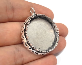 May include: Silver pendant with a round, ornate frame and a blank center for adding a cameo or other embellishment.