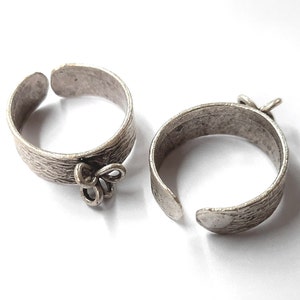 May include: Two silver rings with a textured finish. One ring has a decorative butterfly charm.