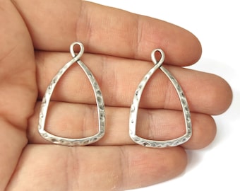 Puede incluir: Dos colgantes de metal de color plateado con textura martillada y forma de lágrima. Cada colgante tiene un bucle en la parte superior para sujetarlo a joyas.