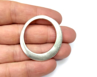 May include: A silver oval ring pendant with a smooth, brushed finish. The ring is thick and has a rounded edge.