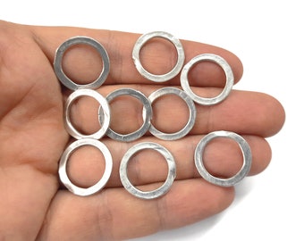 May include: A collection of ten silver-colored metal rings, all of the same size and shape, are displayed on a hand. The rings are smooth and have a slightly textured surface.