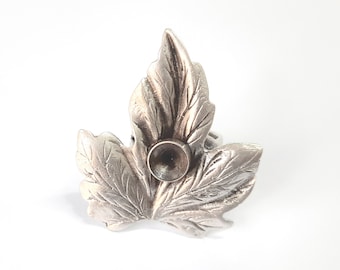 Puede incluir: Anillo de plata con forma de hoja y un centro redondo hueco.