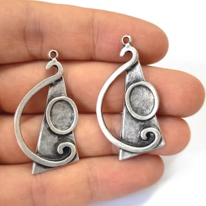 May include: Two silver-toned metal earring blanks with a geometric design. Each blank features a circle and a swirl.