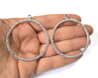 Könnte beinhalten: Zwei silberfarbene Metallreifen mit gehämmerter Textur. Die Reifen haben unterschiedliche Größen und einen Sprungring oben.