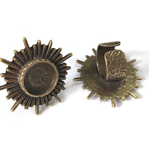 May include: Two bronze sunburst ring blanks with a round bezel for setting a cabochon. The ring blanks are adjustable and have a textured design.