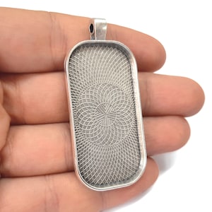 Peut inclure: Plateau de pendentif argenté avec un motif géométrique décoratif. Le plateau est rectangulaire et possède une boucle en haut pour l'accrocher.