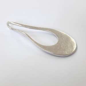 May include: A silver pendant with a smooth, oval shape and a hole in the center. The pendant has a textured surface.