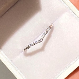 Peut inclure: Une délicate bague en argent avec une bande en forme de V ornée de petits diamants scintillants.