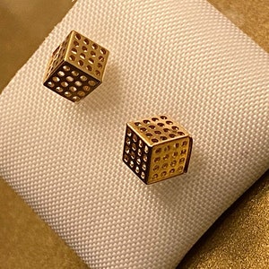 Könnte beinhalten: Ein Paar goldfarbene Ohrringe mit geometrischem Würfeldesign. Die Würfel sind hohl und haben ein Gittermuster.