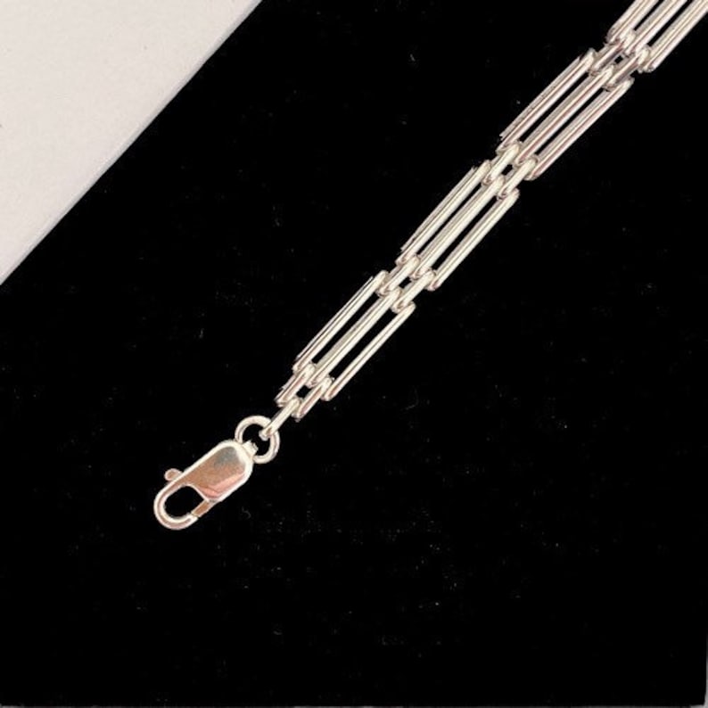Peut inclure: Un bracelet en argent avec un fermoir &agrave; ressort. La cha&icirc;ne est compos&eacute;e de plusieurs barres reli&eacute;es.