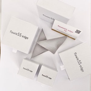 May include: White boxes with the text "flawleSS edge" printed on them. The boxes are arranged in a variety of sizes and positions. A gray cleaning cloth is also visible in the image.