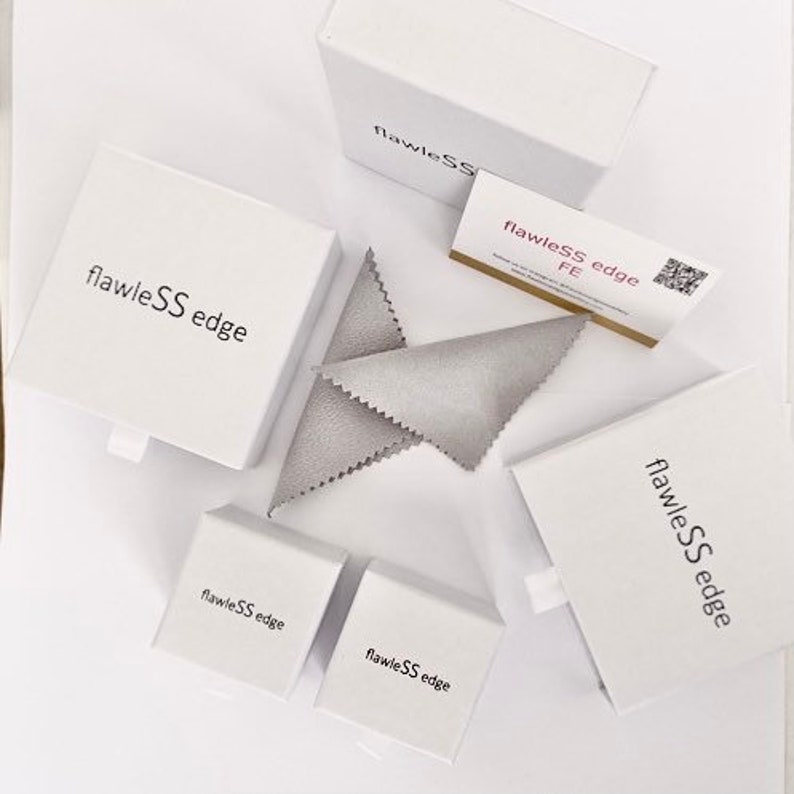 May include: White boxes with the text "flawleSS edge" printed on them. The boxes are arranged in a variety of sizes and positions. A gray cleaning cloth is also visible in the image.