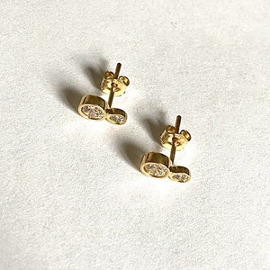 May include: A pair of gold earrings with two clear round stones on each earring.