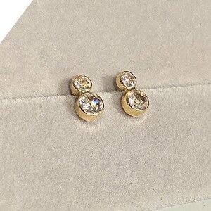 May include: A pair of gold earrings with two clear round stones on each earring.