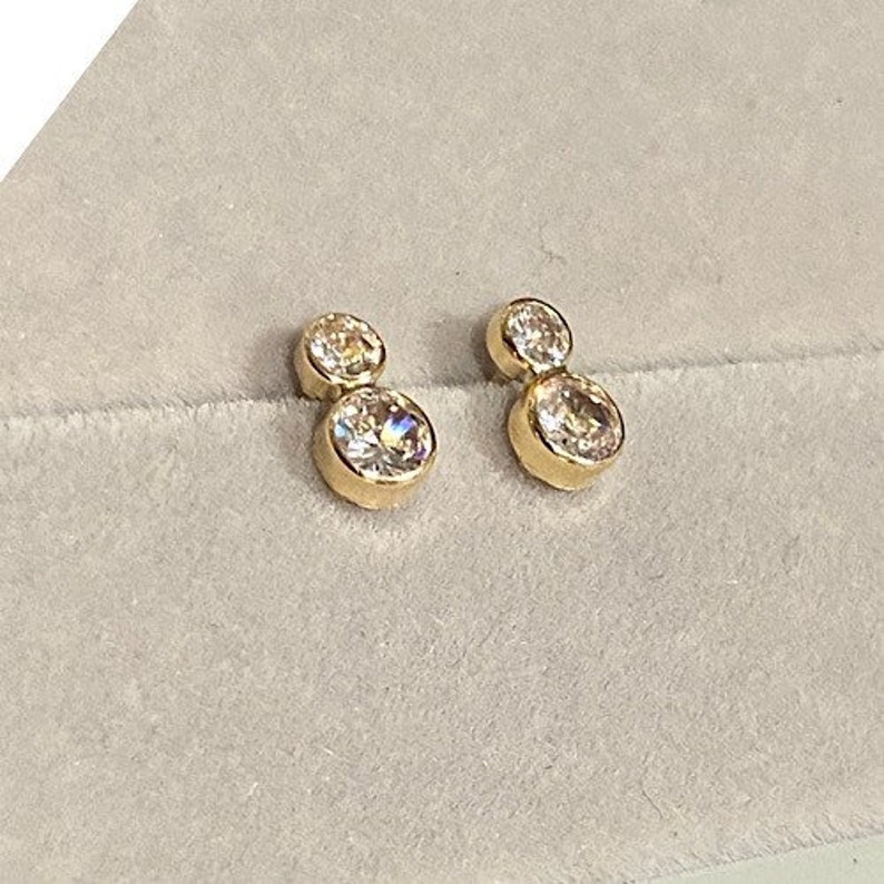 May include: A pair of gold earrings with two clear round stones on each earring.
