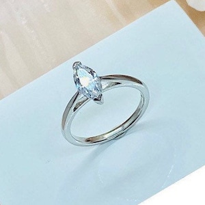 Puede incluir: Un anillo de plata con una piedra preciosa transparente de forma marquesa.