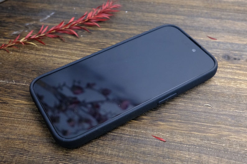 以下が含まれることがあります： 滑らかでマットな仕上がりの黒い携帯電話ケース。ケースは柔らかく柔軟な素材で作られており、画面の周りに傷から保護するための隆起した縁があります。