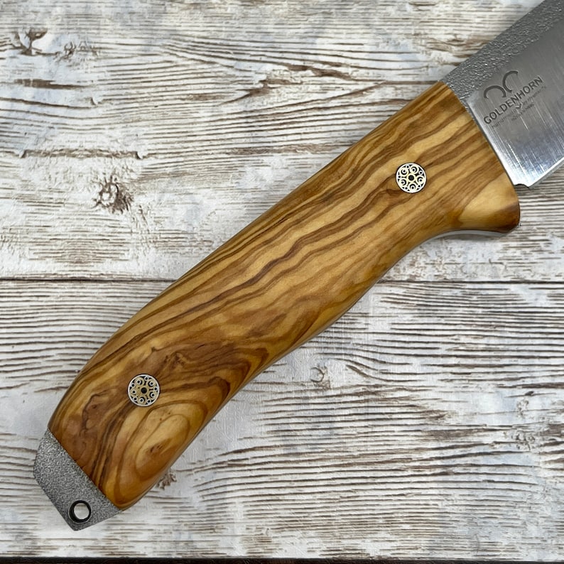Pu&ograve; includere: Un coltello con manico in legno e lama in acciaio inossidabile. Il manico &egrave; in legno di ulivo e presenta due accenti metallici decorativi. La lama &egrave; incisa con le parole "Goldenhorn" e "Made in Germany".