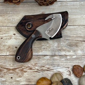 May include: A knife with a brown wooden handle, a curved blade and a leather sheath. The blade has a hook on the end and the text "GOLDENHORN" is engraved on the blade.