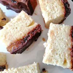 May include: Close-up of several slices of cake with a layer of orange marmalade and topped with a layer of dark chocolate.