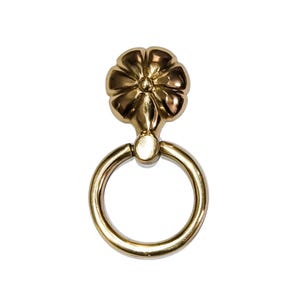 Può includere: Un tirarello ad anello in metallo dorato con una parte superiore decorativa a forma di fiore.