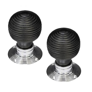 May include: Two black wood door knobs with a chrome base and a grooved design.