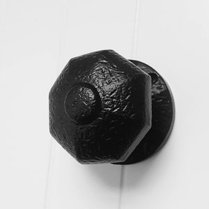 May include: Black octagonal door knob with a textured finish.