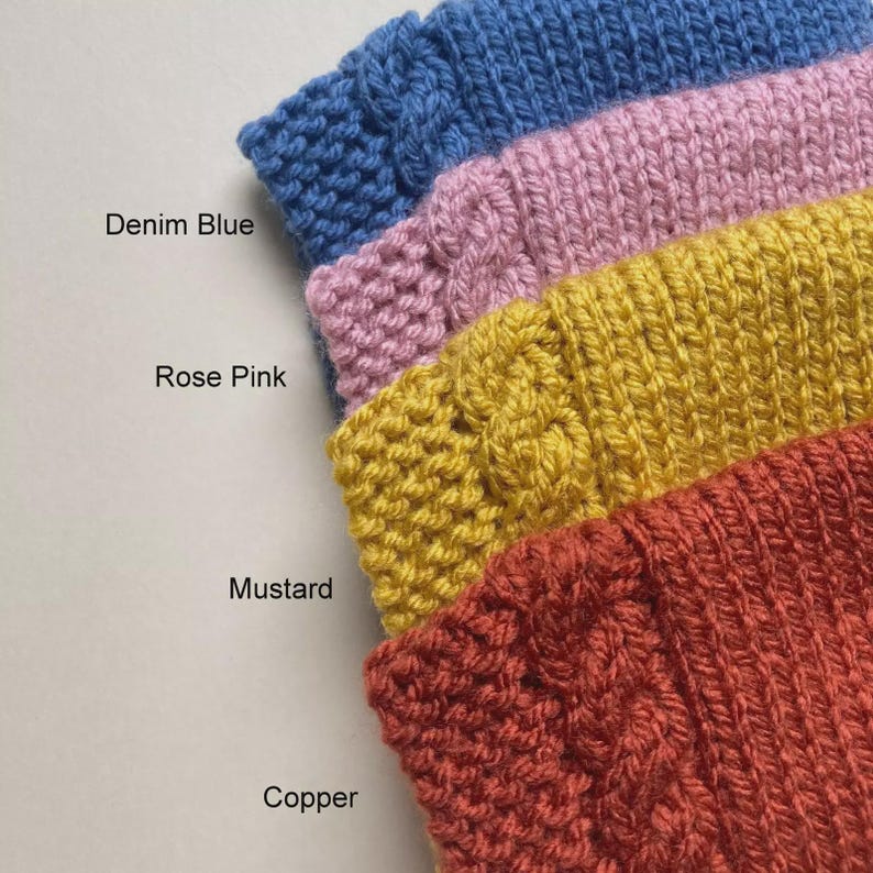 Puede incluir: Primer plano de cuatro muestras de tejido de punto en azul denim, rosa, mostaza y cobre. Los nombres de los colores est&aacute;n impresos en el lado izquierdo de la imagen. La textura de punto es visible, con un dise&ntilde;o de punto de cable en las muestras de mostaza y cobre.